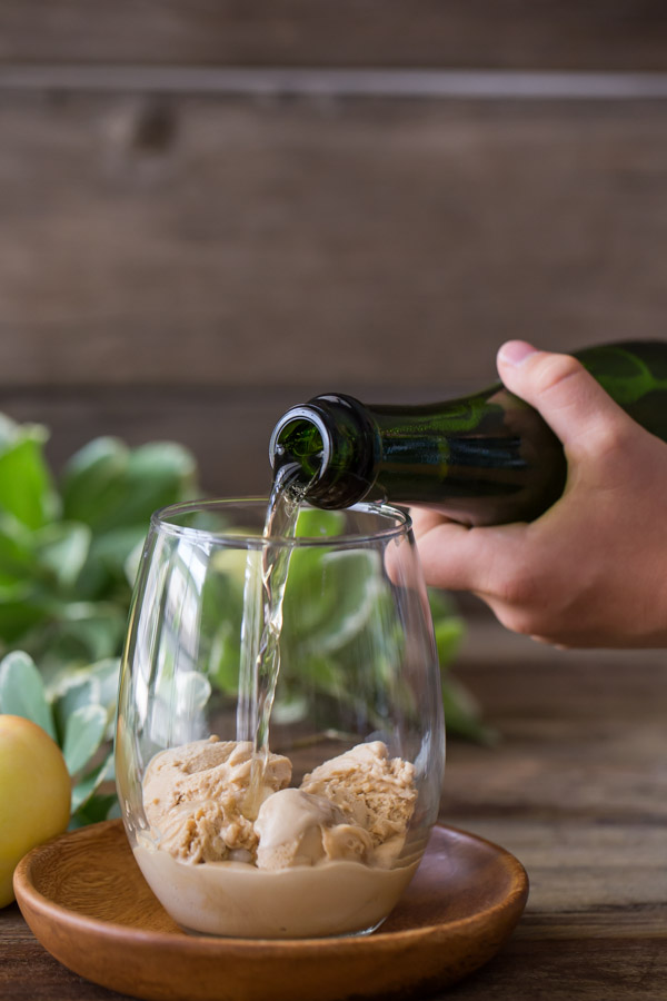 A glass with Salted Caramel Ice Cream in it, and some Sparkling Apple Cider being poured on top.  