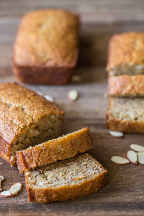 Healthier Banana Bread mini loaf that has been sliced, with a whole mini loaf and another sliced mini loaf in the background.