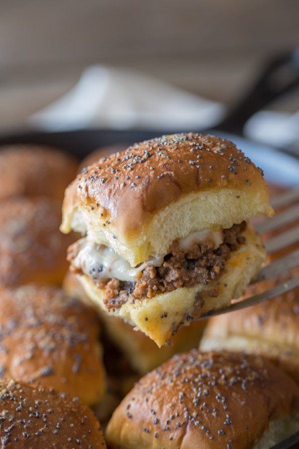 A Party Bun Style Sloppy Joe on a serving spatula, with the rest of the Party Bun Style Sloppy Joes in a cast iron skillet in the background.