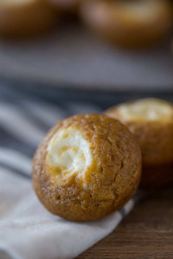 Mini Pumpkin Cheesecake Muffins - Super pop-able, bite sized pumpkin muffins with a creamy cheesecake center. 