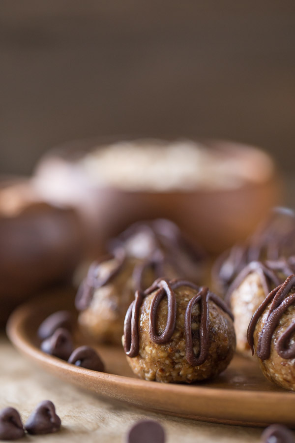 No Bake Energy Bites on a wood plate, drizzled with melted chocolate. 