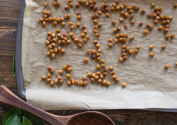 Roasted chickpeas on a parchment paper lined baking sheet for the Turkey Farro Salad With Candied Chickpeas.