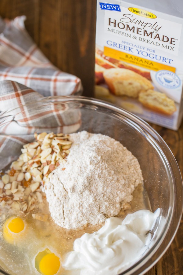 A large glass bowl with all the ingredients for the Banana Muffins in it, sitting next to a box of Fleischmann’s Simply Homemade Muffin & Bread Mix, banana flavor.
