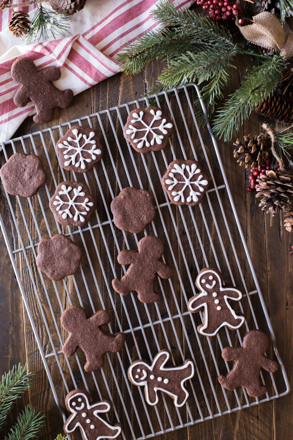 A cooling rack with Snowflake and Gingerbread Men Chocolate Cut-Out Cookies, with some decorated with icing.