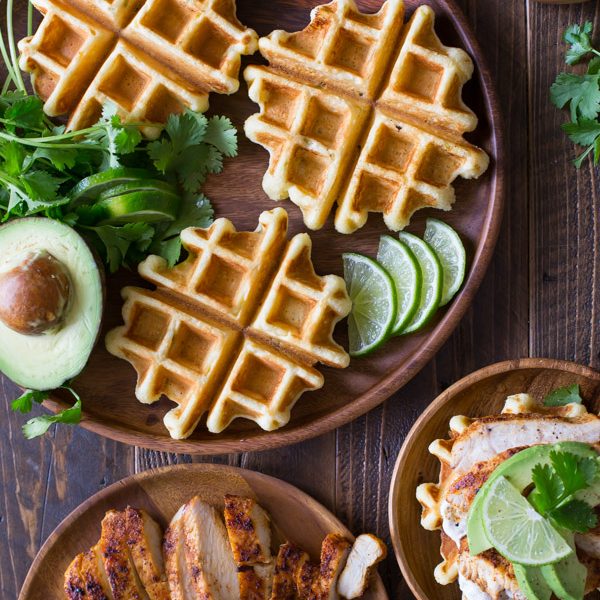Green Chile Chicken Waffletada - A mini cornbread waffle served tostada style, topped with a green chile cream, grilled chicken, and avocado!