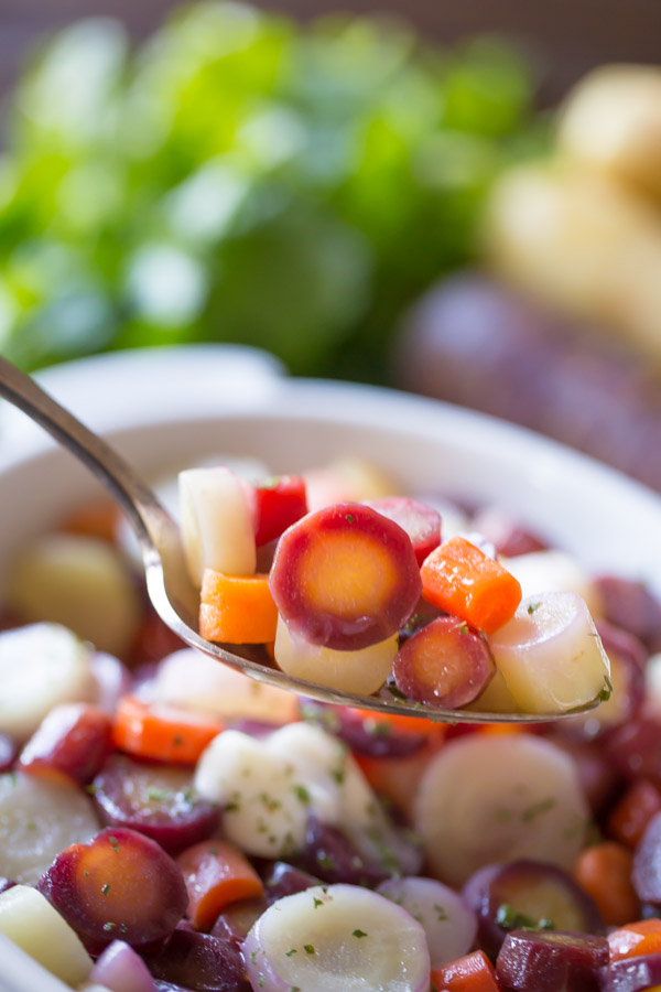 Honey Roasted Rainbow Carrots on a serving spoon held over the serving dish of carrots.