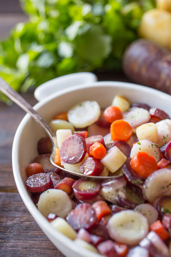 Honey Roasted Rainbow Carrots in a serving dish with a serving spoon in it.