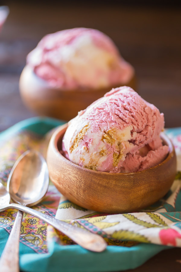 Homemade Raspberry Cheesecake Ice Cream in two small wood bowls with two spoons next to the bowl in front.  