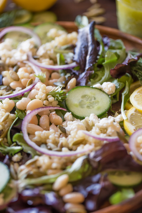 White Bean Couscous Salad With Lemon Vinaigrette on a large wood plate.