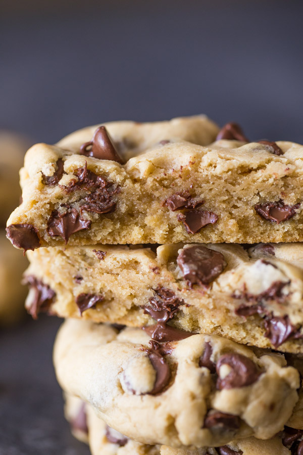 An Ultimate Chocolate Chip Cookie cut in half, stacked on top of two whole cookies.