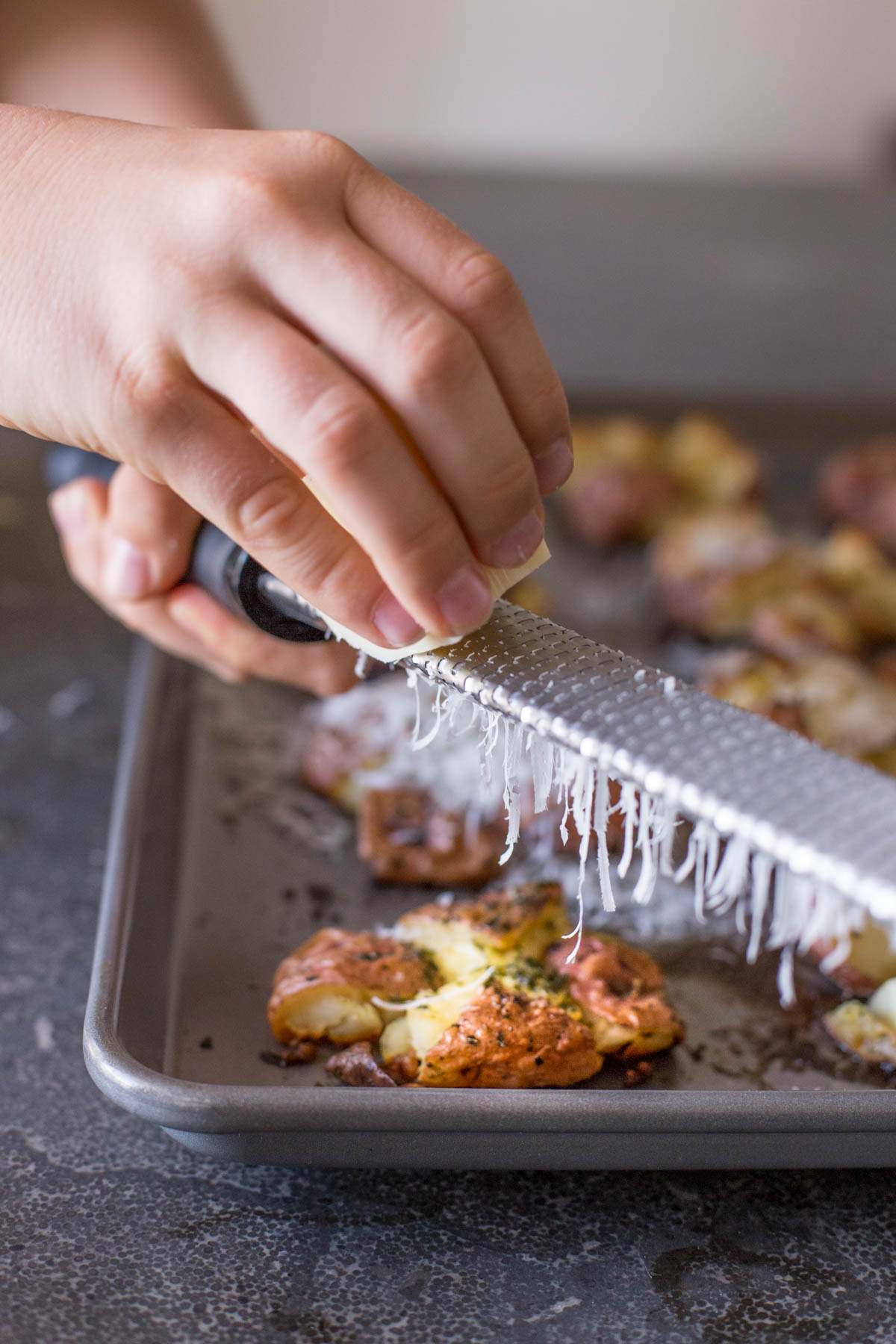 Fresh parmesan cheese being grated over the Smashed and Roasted Potatoes.