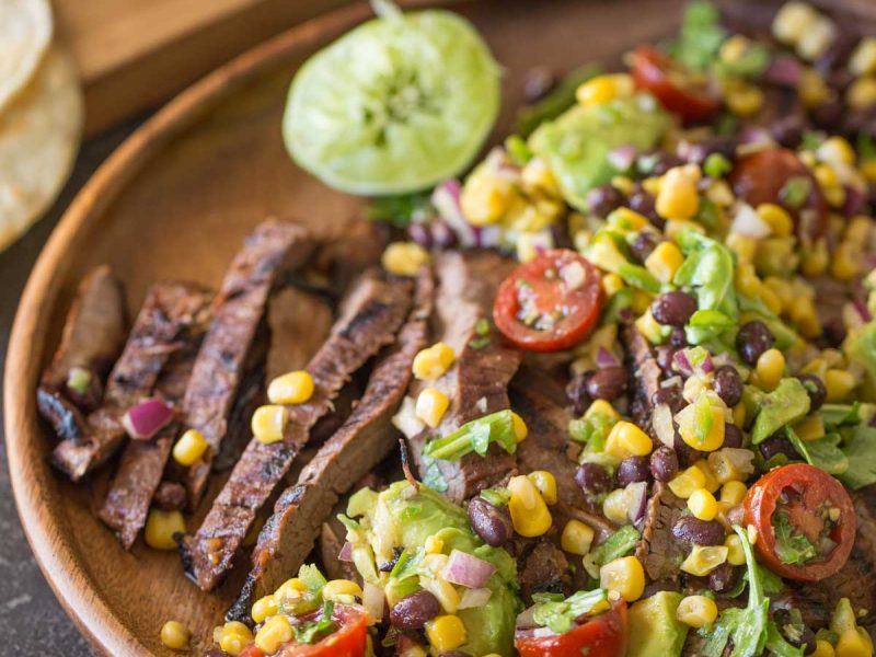 Grilled, marinated flank steak sliced thinly, wrapped in a warm corn tortilla and topped with a fresh mixture of avocado, tomato, corn, and black beans!