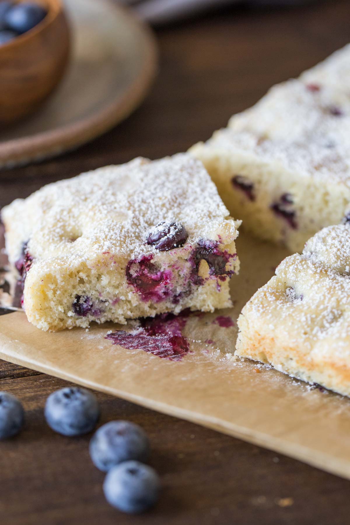 Buttermilk Blueberry Snack Cake sliced on a piece of parchment paper.