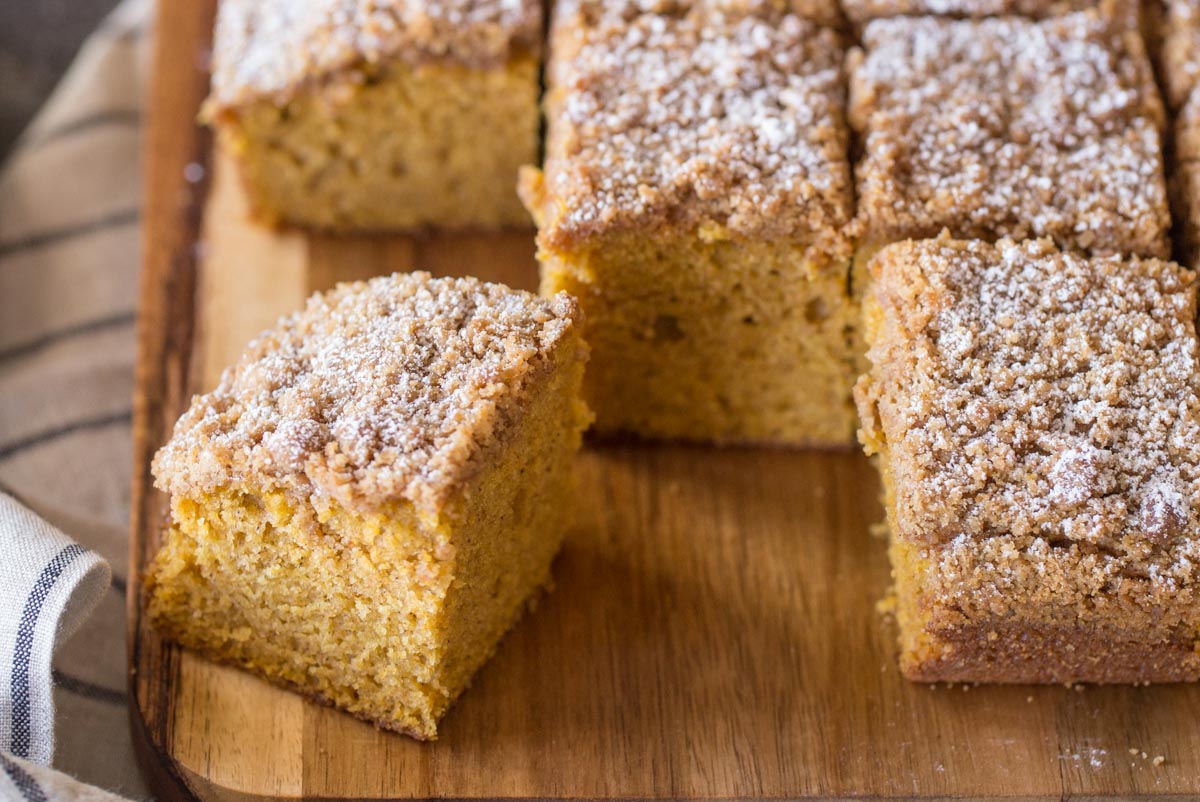 Pumpkin Spice Coffee Cake cut into square servings on a cutting board.