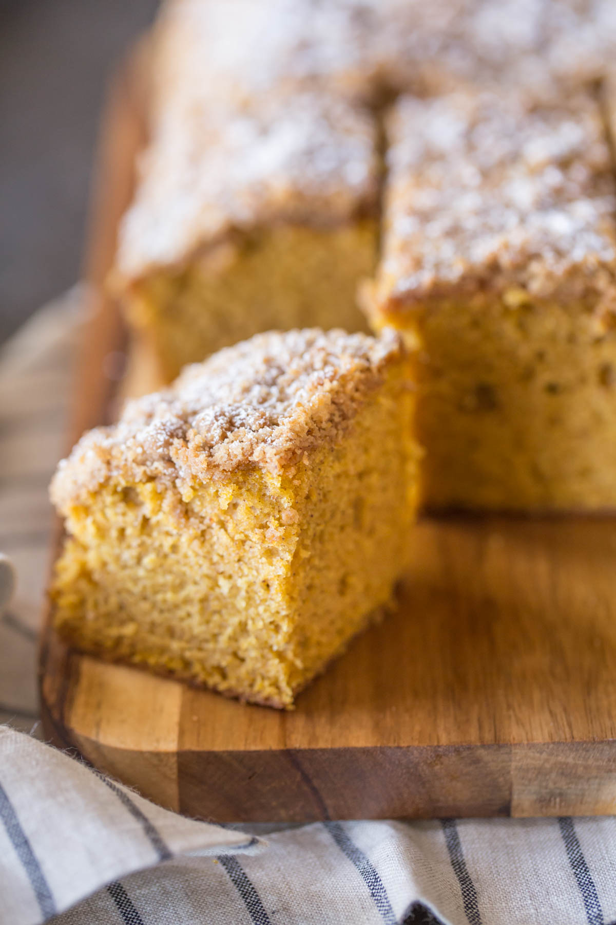 Pumpkin Spice Coffee Cake sliced into square servings on a cutting board.