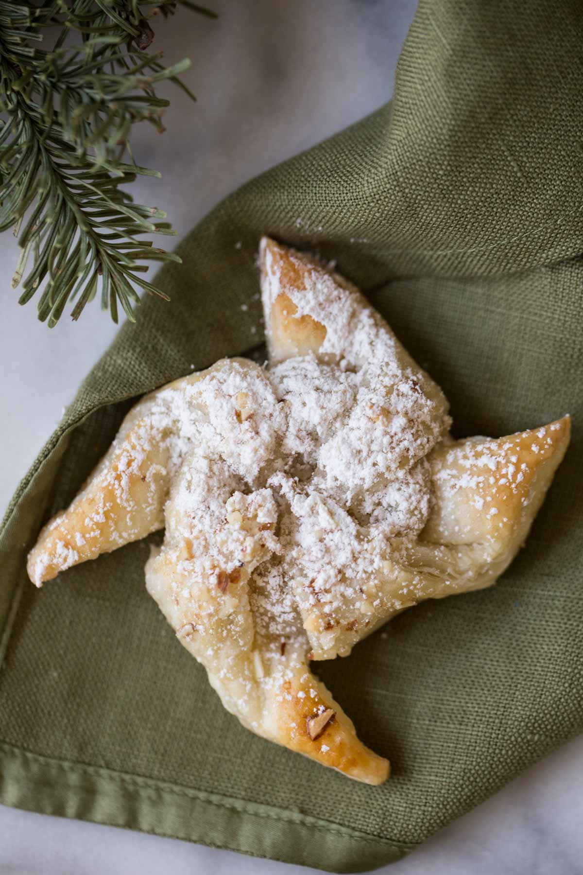 A Make Ahead Almond Pinwheel sitting on a green cloth napkin. 