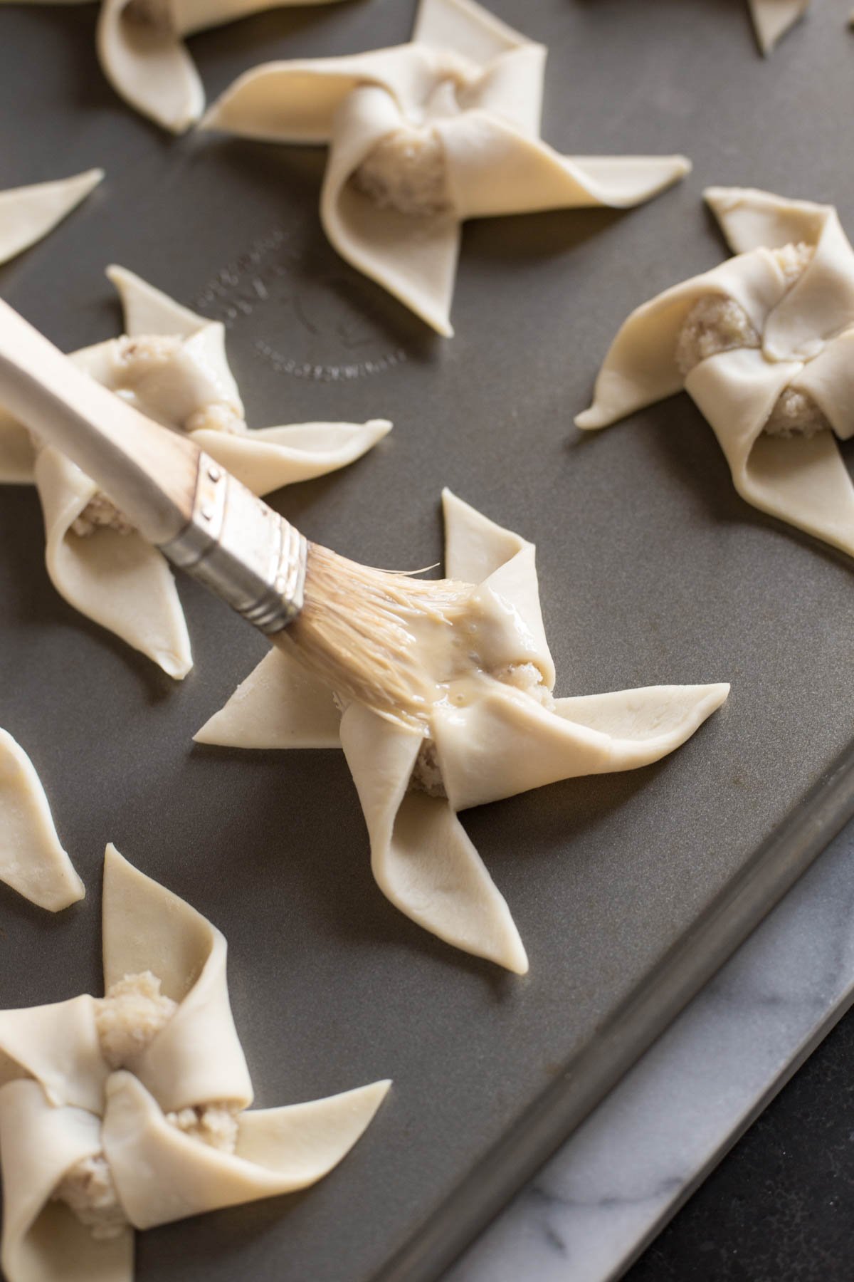 Make Ahead Almond Pinwheels on a baking sheet being brushed with the egg wash.   