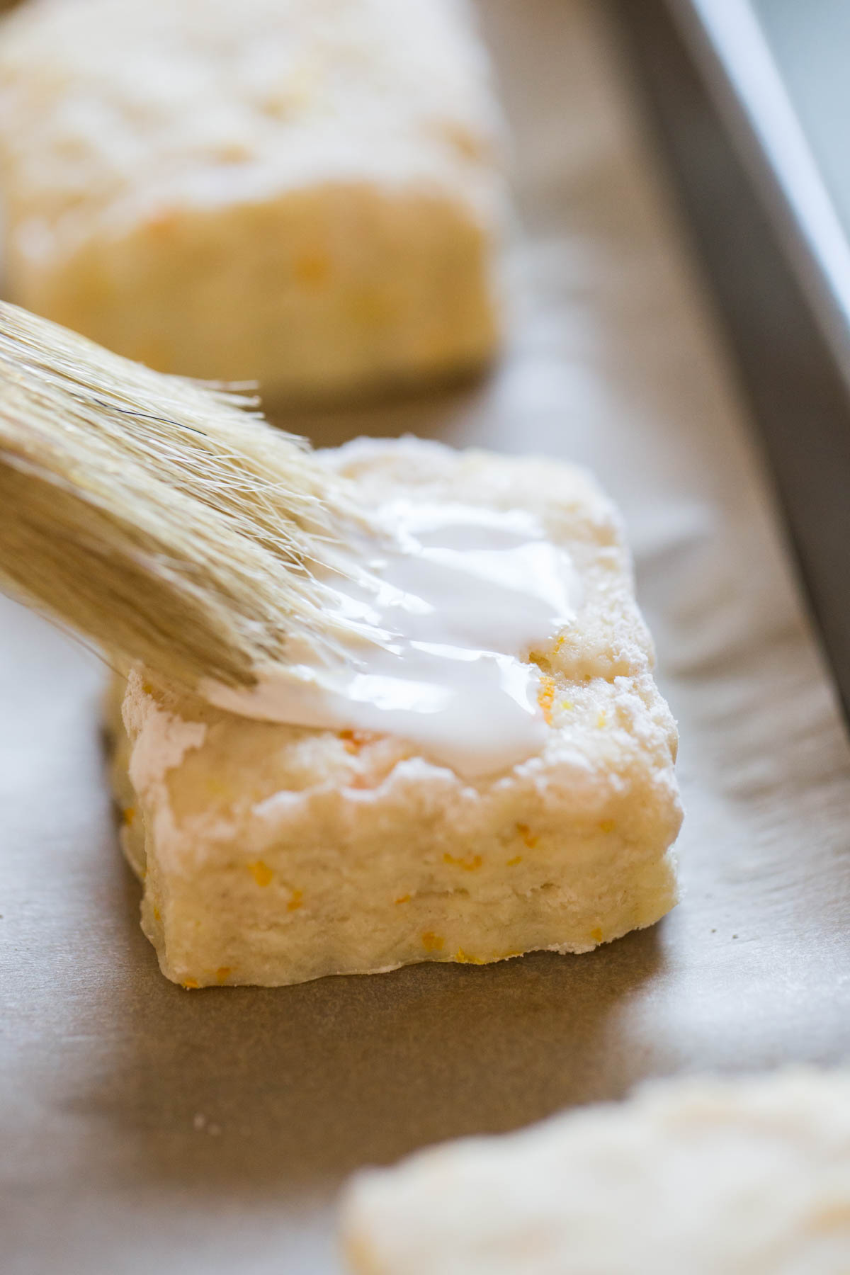 Heavy cream being brushed onto a Mini Orange Cream Scone.  