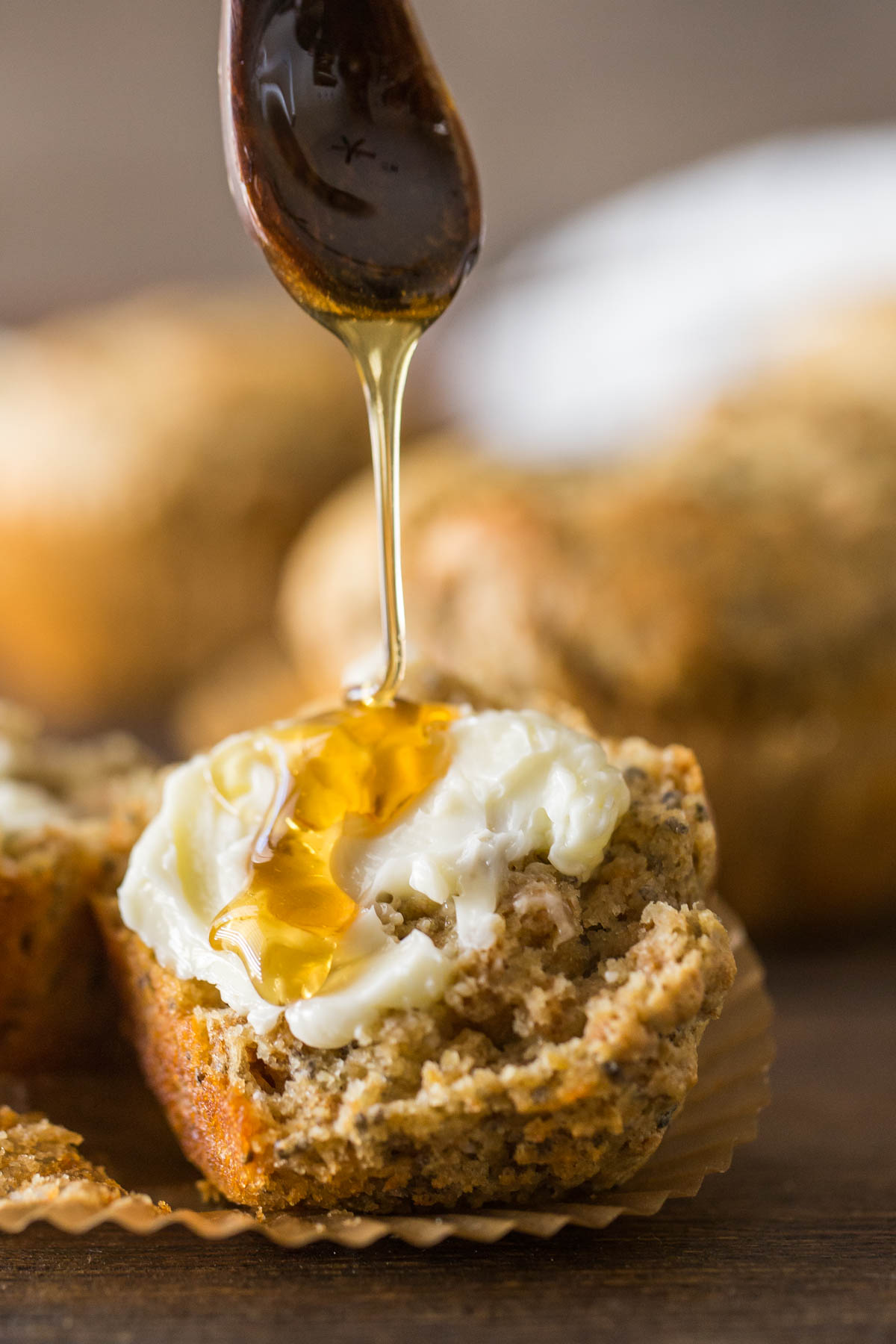 A half of a Honey Bran Muffin with butter on it and honey being drizzled over it.