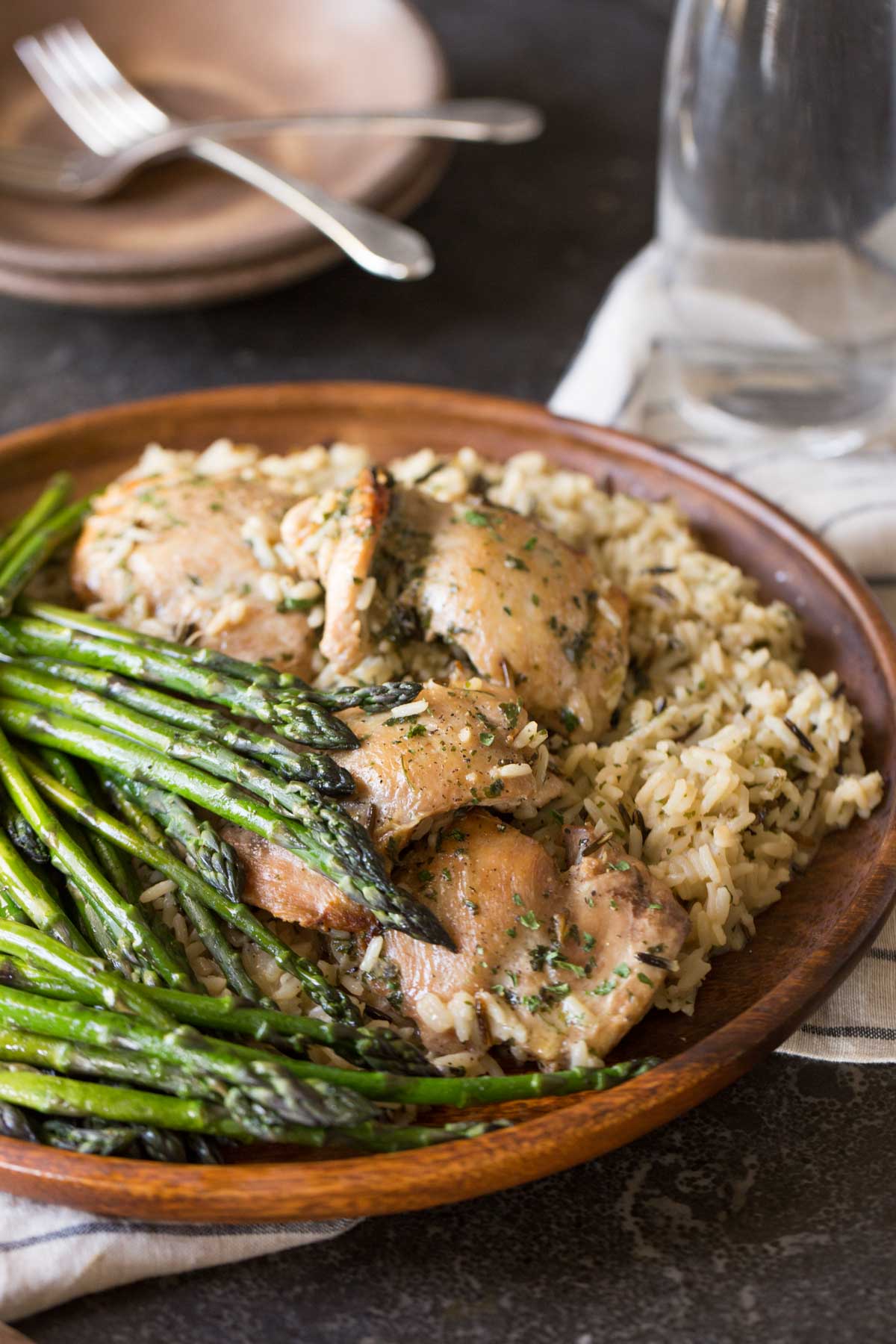 One Pot Chicken and Rice Dinner on a large serving plate, with some plates, forks and a glass in the background. 