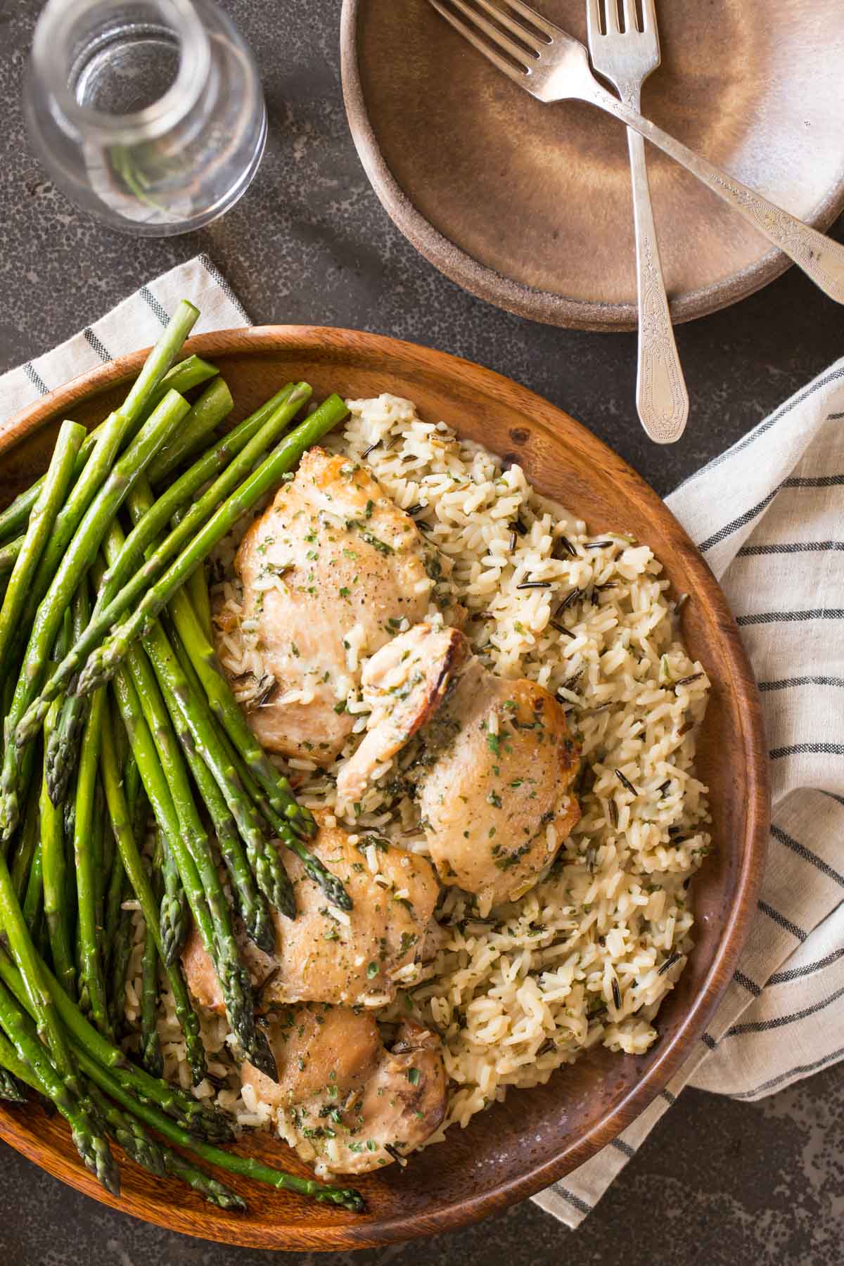 One Pot Chicken and Rice Dinner on a large serving plate, sitting next to some plates, forks and a glass. 