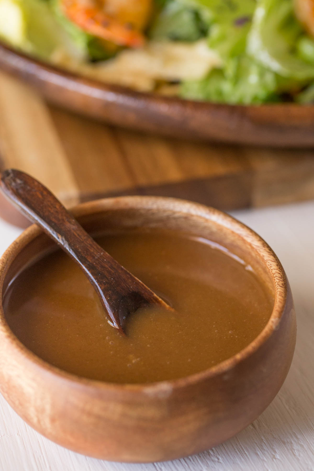 A small wood bowl of the Spicy Peanut Dressing with a little wooden spoon in it. 