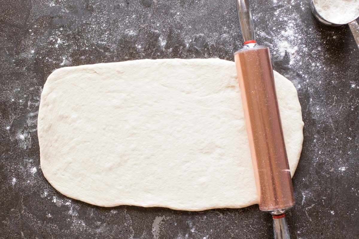 Fresh Buttery Garlic Breadsticks dough rolled out with rolling pin.
