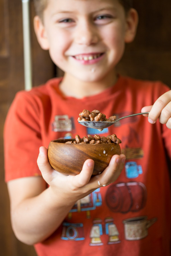 Little boy holding a small bowl of Annie's Cocoa Bunnies and milk.