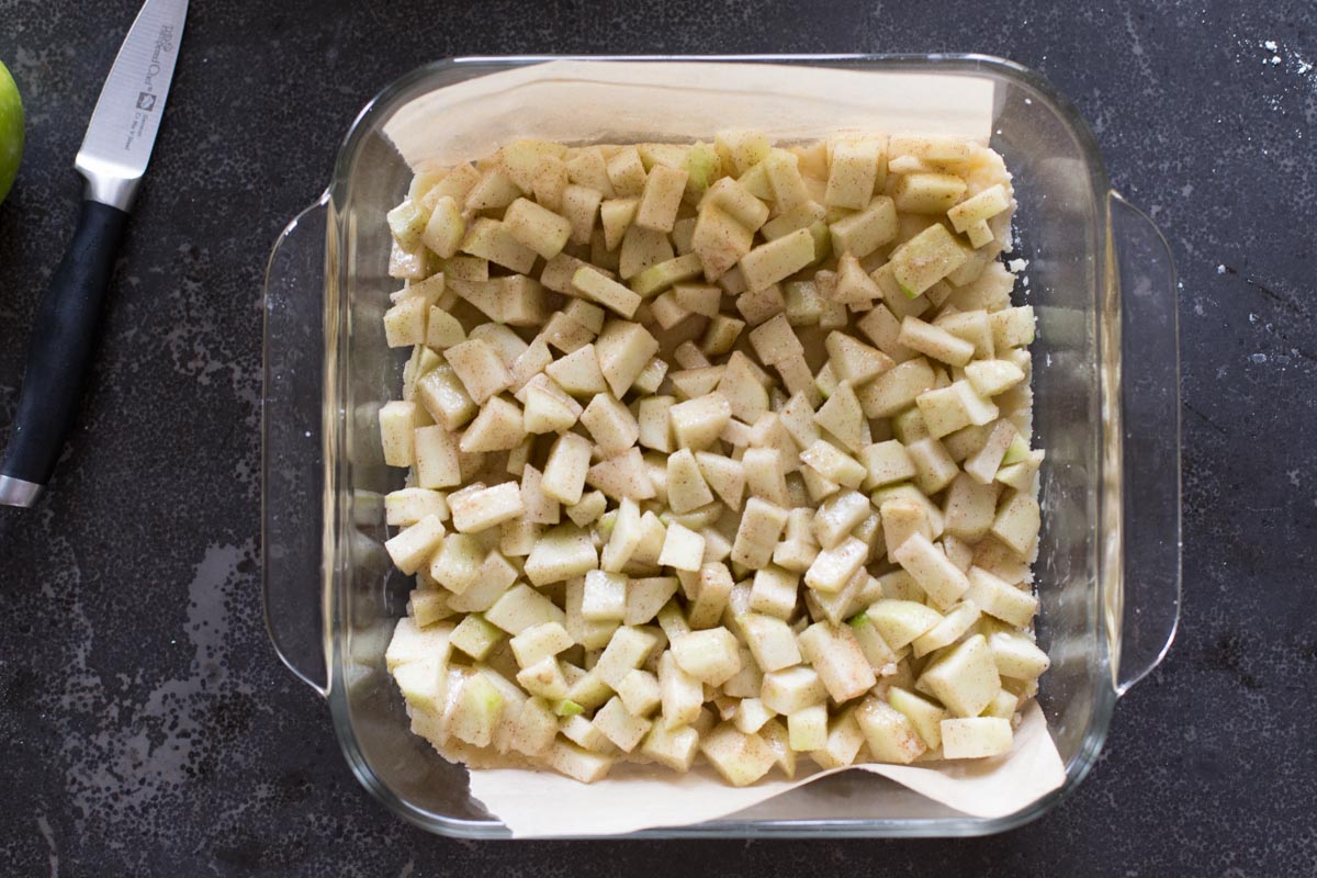 The Apple Pie Crumb Bars filling in a parchment paper lined baking dish.