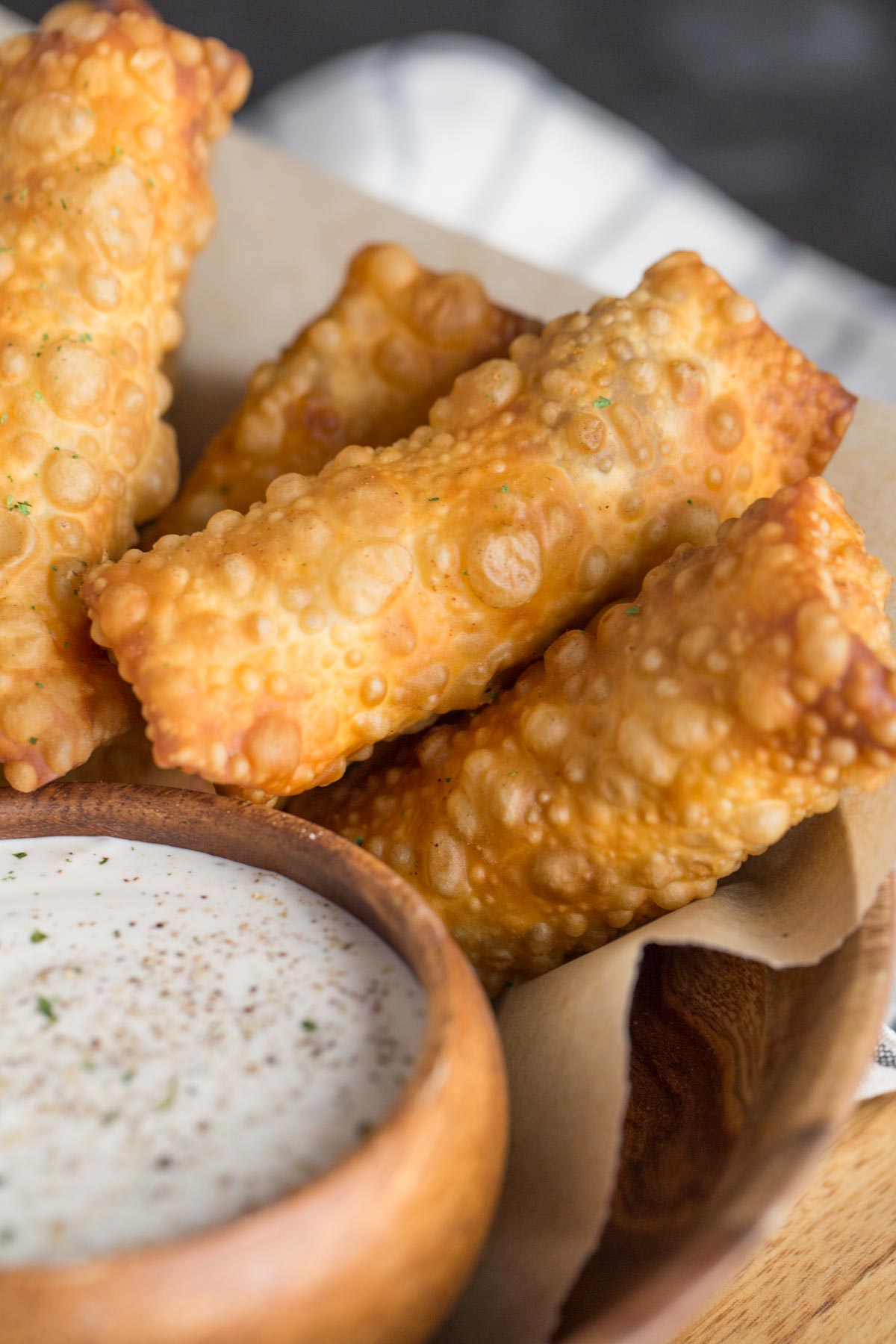 Fried Sloppy Joe Rolls in a wood bowl, along with a small wood bowl of ranch dip. 
