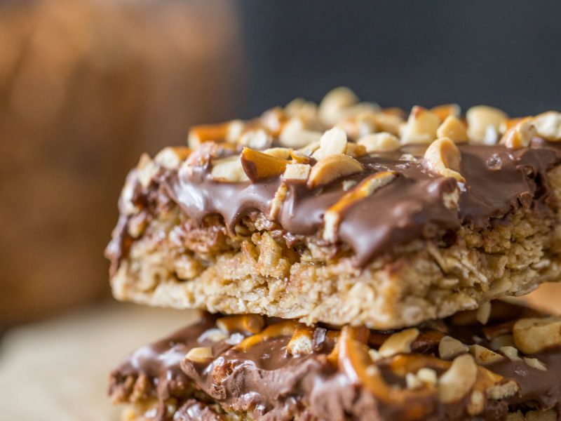 A side view of the chewy oat layer and chocolate peanut butter layer of two stacked Oh Henry Bars