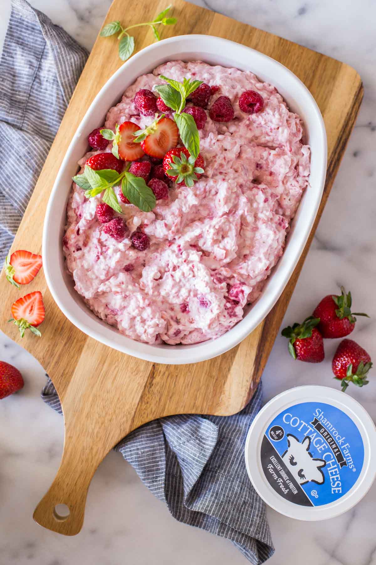 Top down view of fluffy pink salad in a dish garnished with fresh berries and mint.