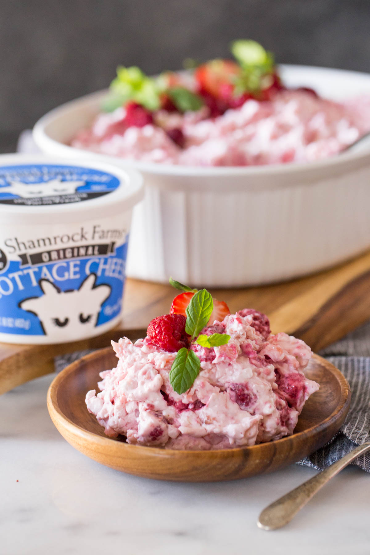 Very Berry Fluffy Salad dished out into a bowl with Shamrock Farms cottage cheese in the background.