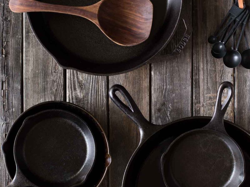 Various sizes of cast iron skillets on a wooden board.