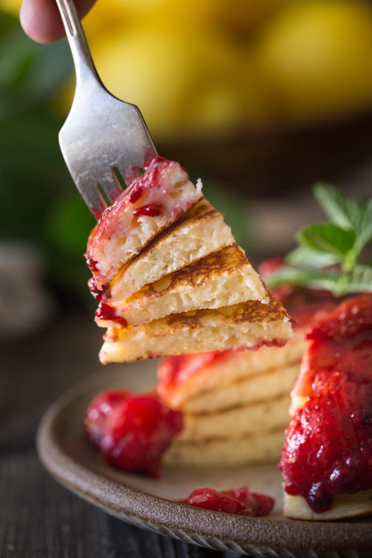 A forkful of Lemon Ricotta pancakes and fresh berry sauce.