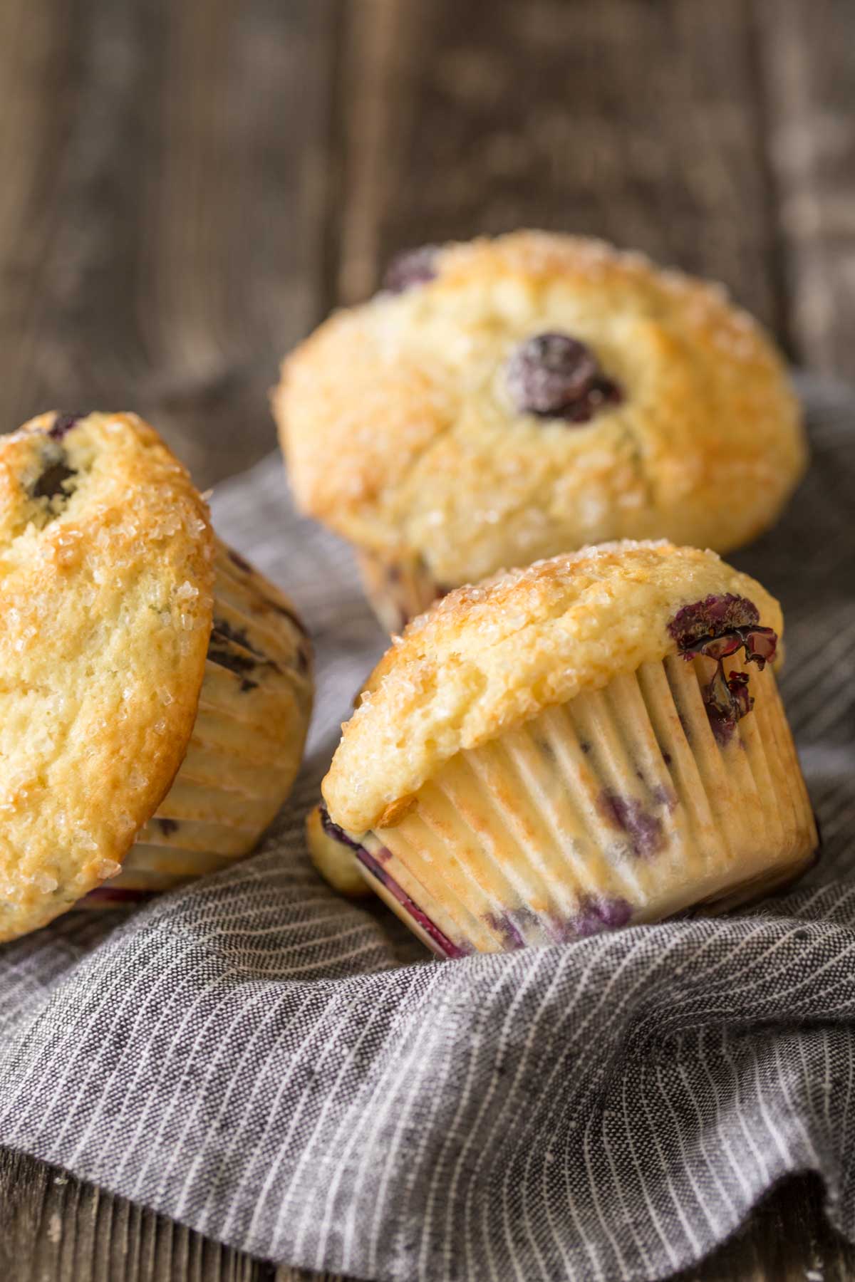 Three Best Ever Buttermilk Blueberry Muffins on a kitchen towel.
