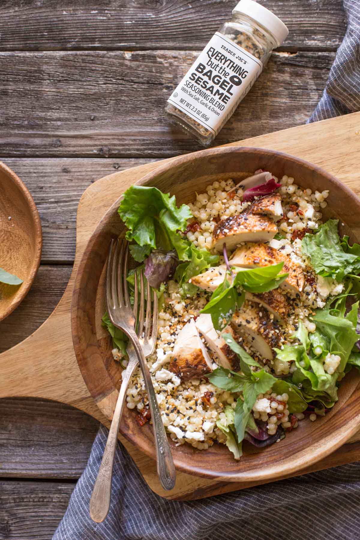 Israeli Couscous Salad with Honey Lemon Vinaigrette in a wooden bowl on a wooden cutting board with Everything But the Bagel Seasoning. 