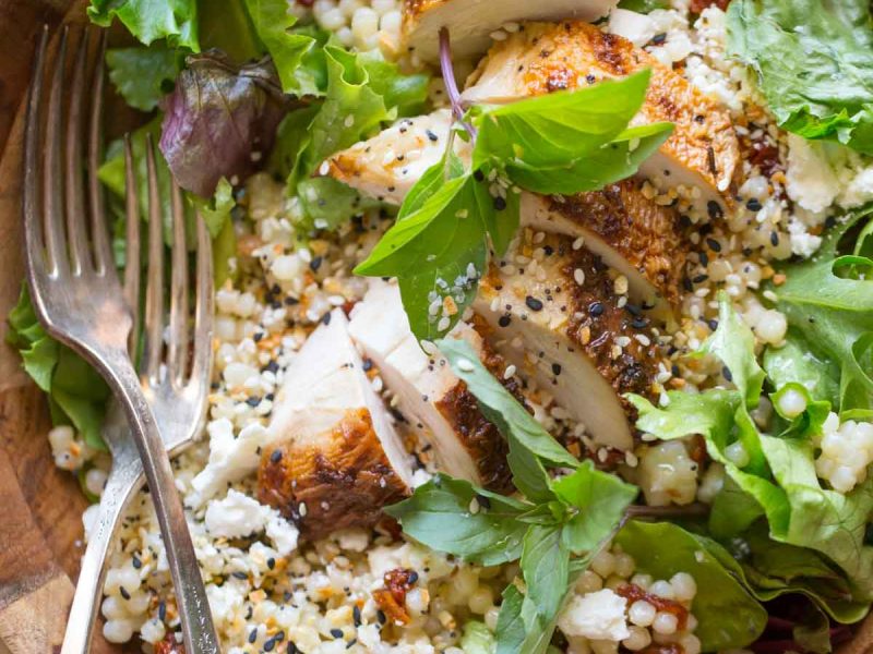 Israeli Couscous Salad with Honey Lemon Vinaigrette in a wooden bowl on a wooden cutting board.