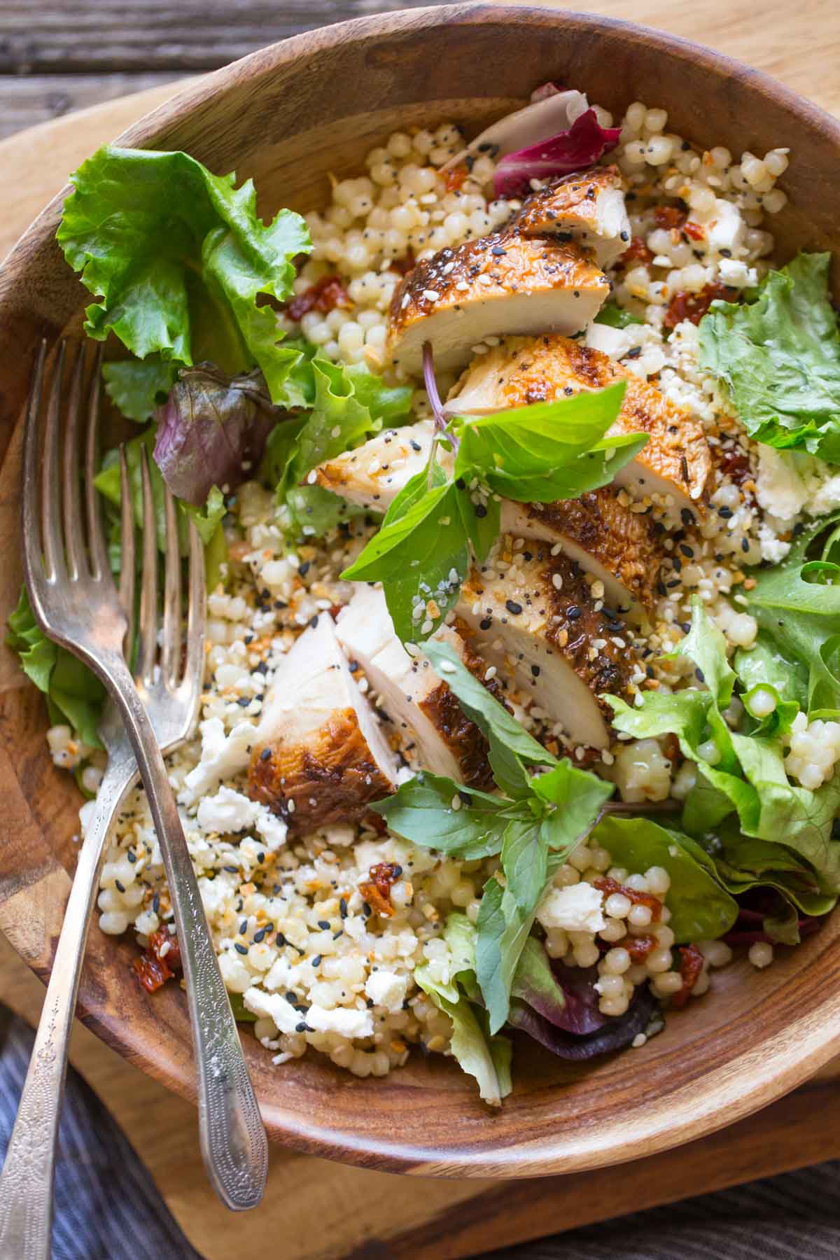 Israeli Couscous Salad with Honey Lemon Vinaigrette in a wooden bowl on a wooden cutting board.
