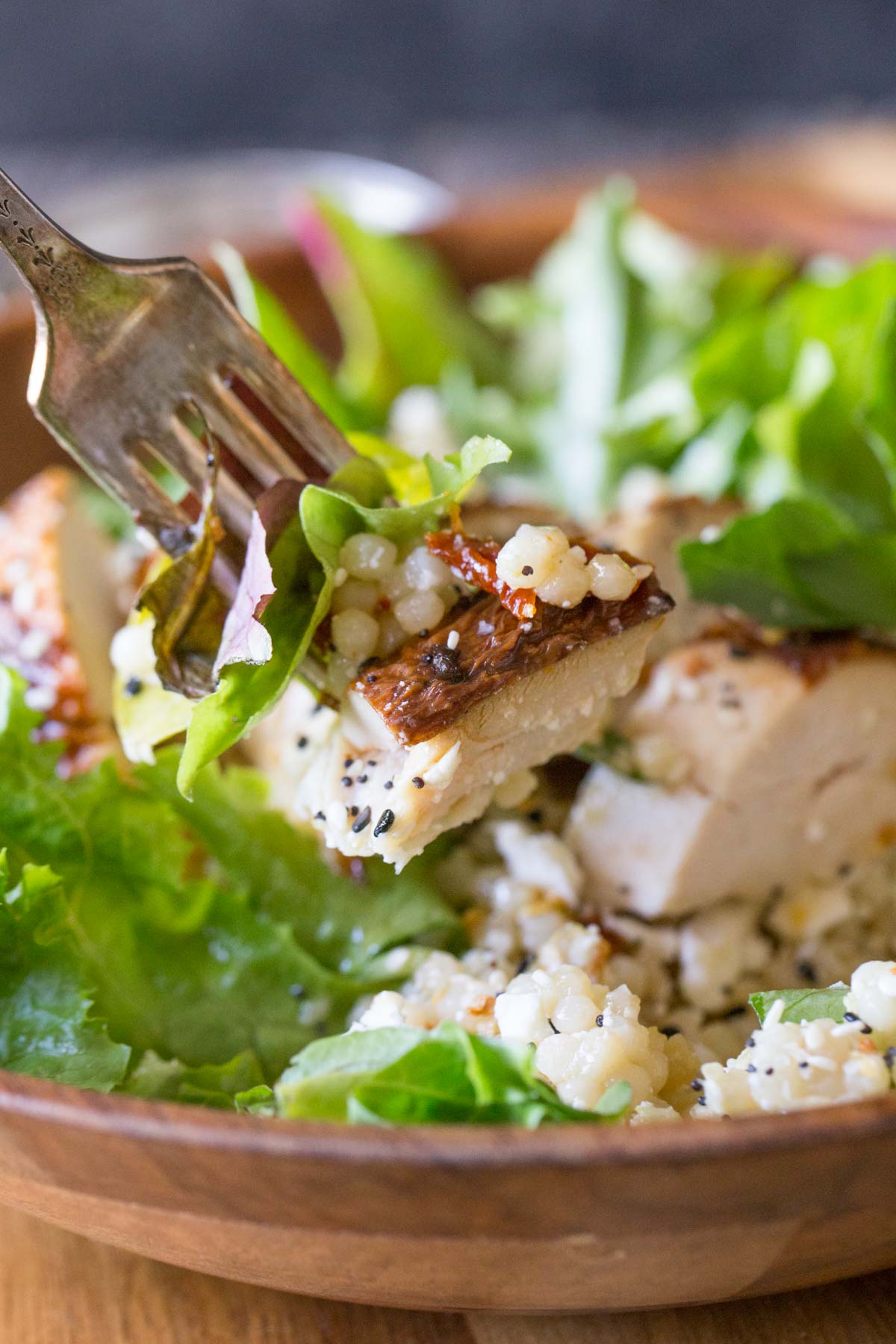 Israeli Couscous Salad with Honey Lemon Vinaigrette in a wooden bowl with a forkful in the foreground.