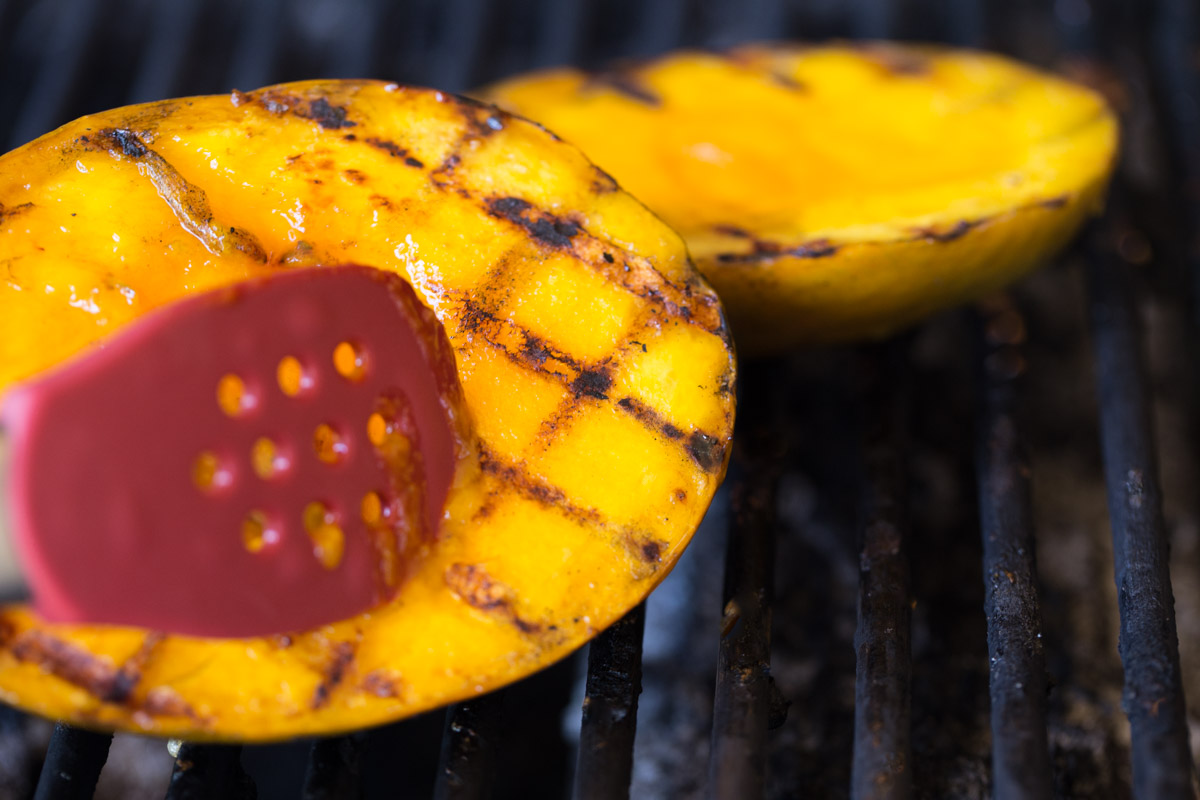 Mango halves on a grill with grill marks.