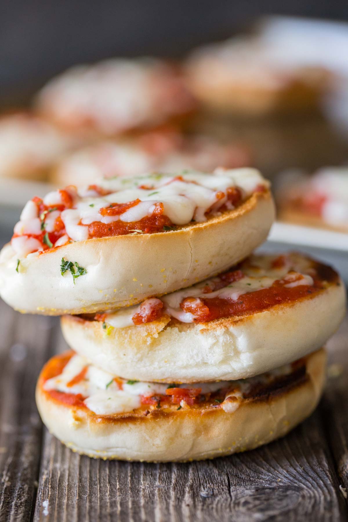 Close up of a stack of Homemade Mini Bagel Pizza on a wooden background.