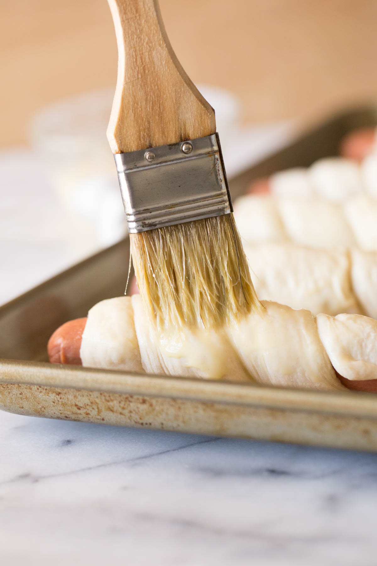 Hot dogs wrapped in dough brushed with egg.
