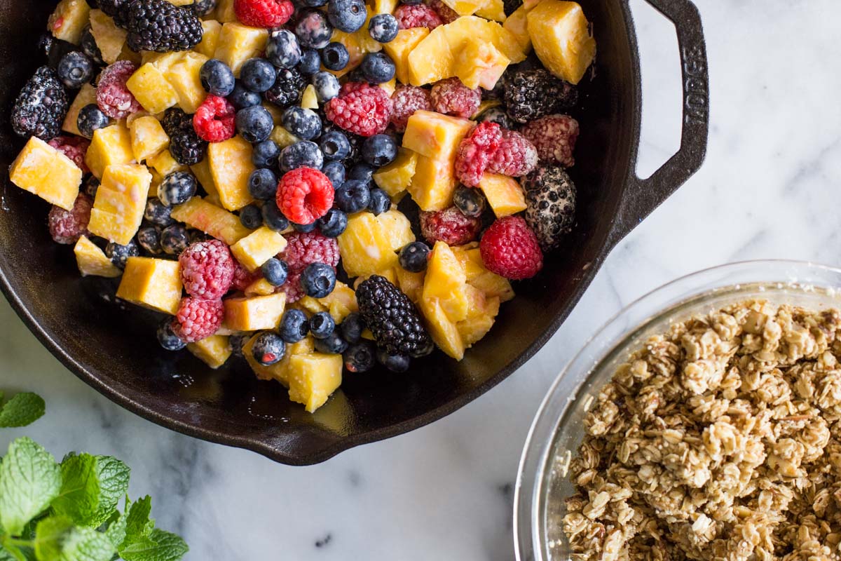 Mango and berries in a cast iron skillet ready to bake.