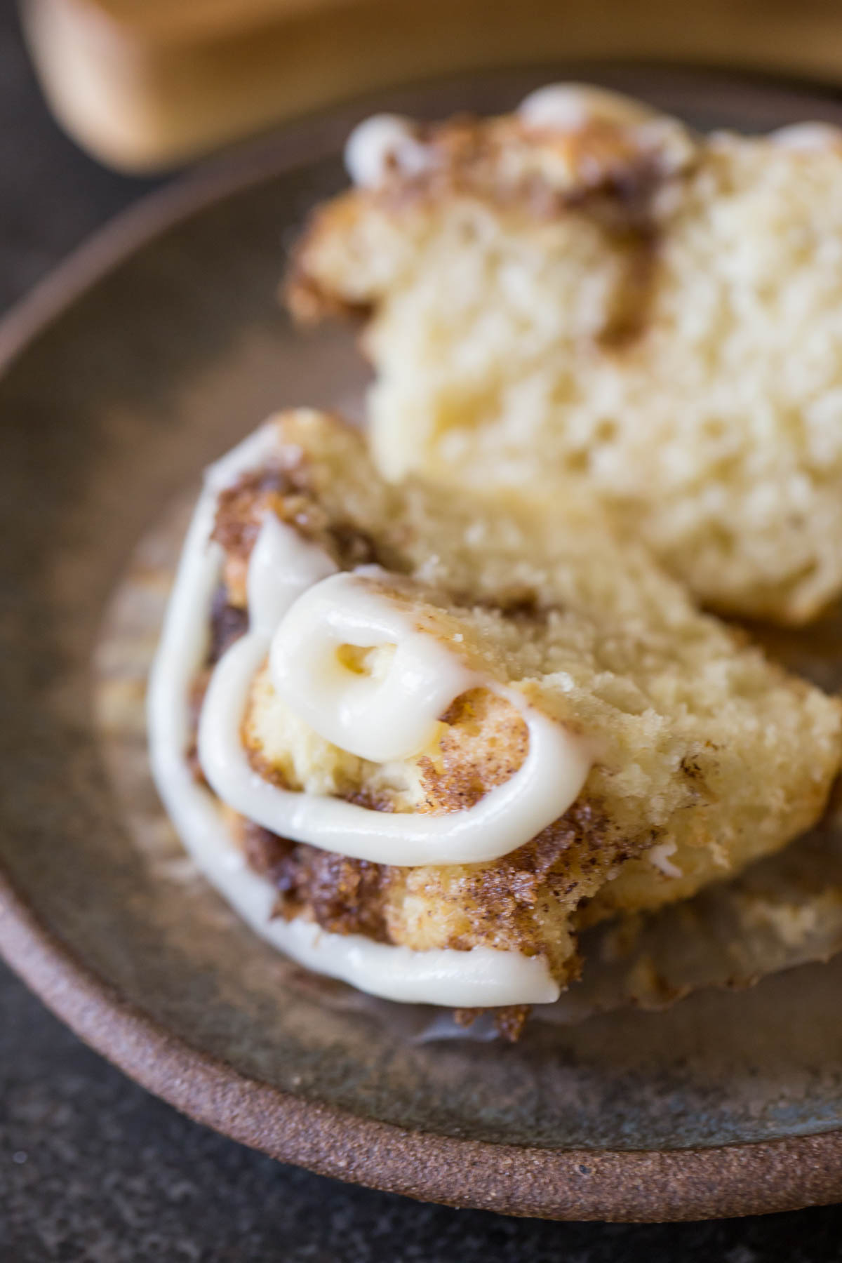 A close up of a halved Cinnamon Roll Muffins with a cream cheese icing swirl. 