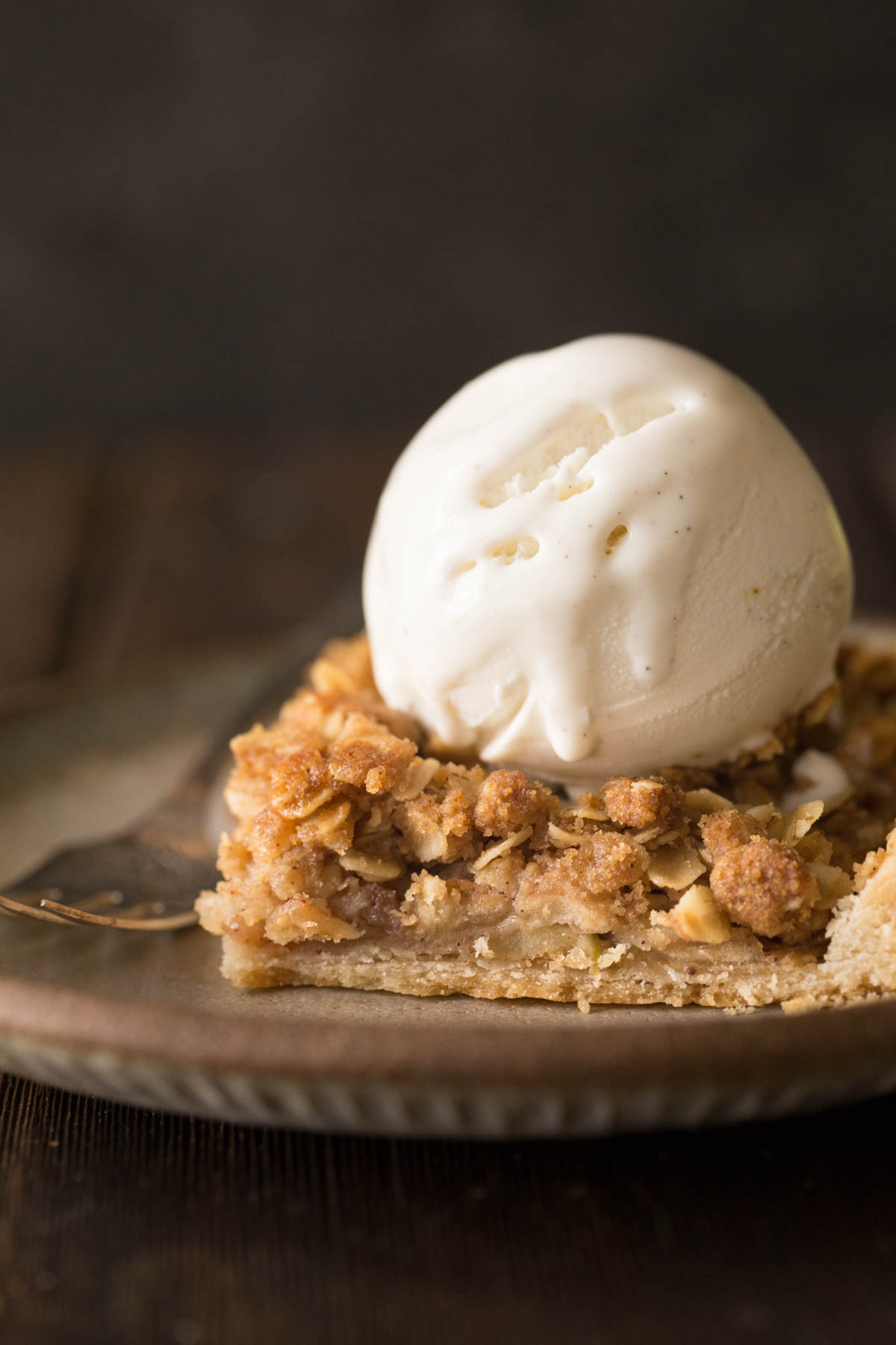 A close up view a piece of Dutch Apple Slab Pie with a scoop of vanilla ice cream on top.