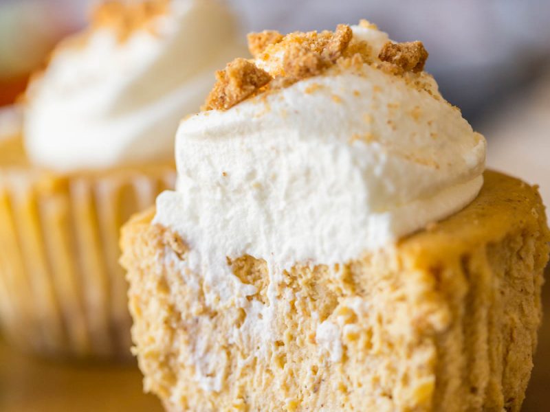 Close up shot of the inside of pumpkin spice cheesecakes topped with whipped cream