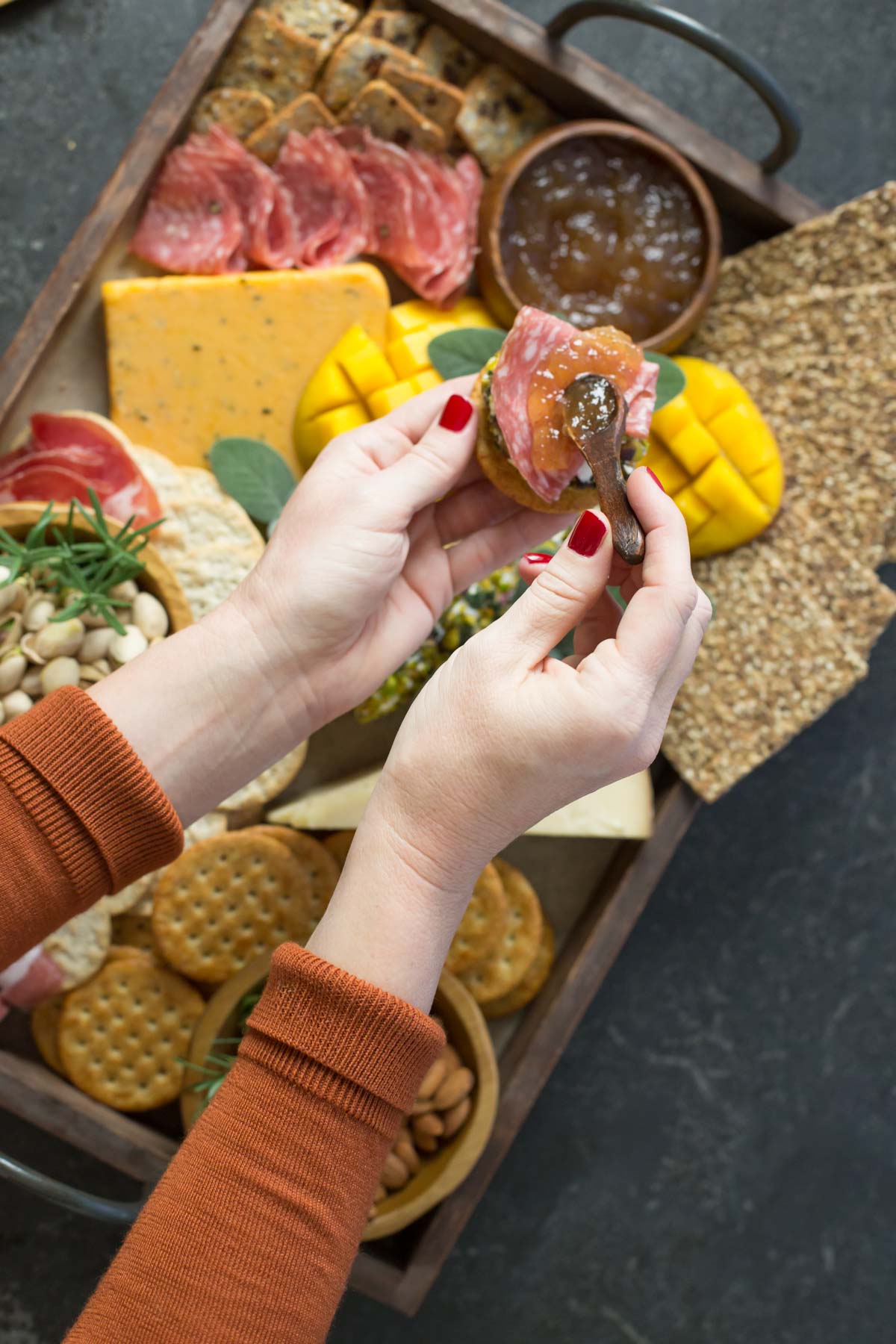 Hands in shot above view of charcuterie. 