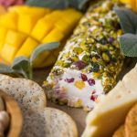 Close up view of Pistachio Crusted Cheese Log displayed as part of a charcuterie.