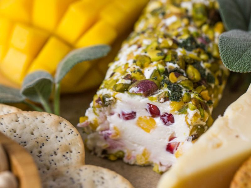 Close up view of Pistachio Crusted Cheese Log displayed as part of a charcuterie.